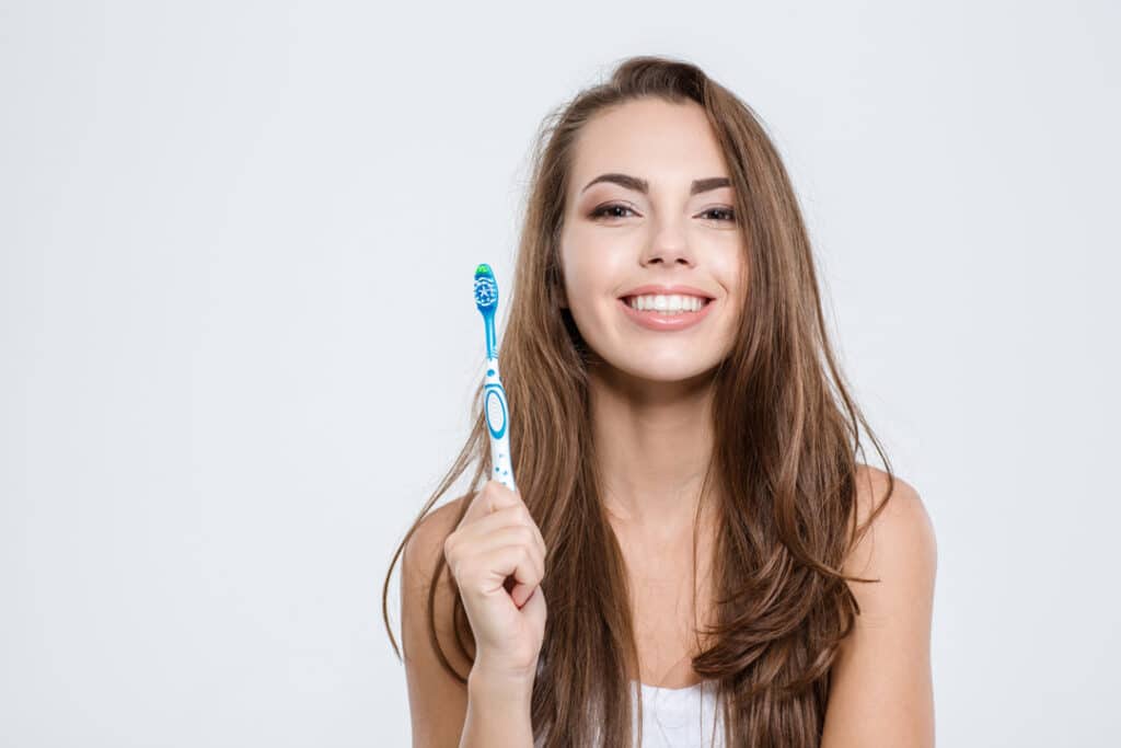 A woman smiling while holding a toothbrush.